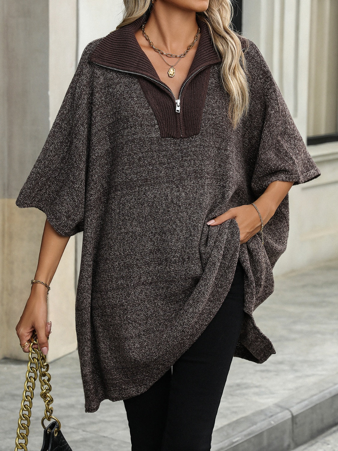 Femme portant un poncho marron à col zippé, manches courtes, avec un sac à chaîne dorée. Mode automne, style décontracté chic, tendance 2023.