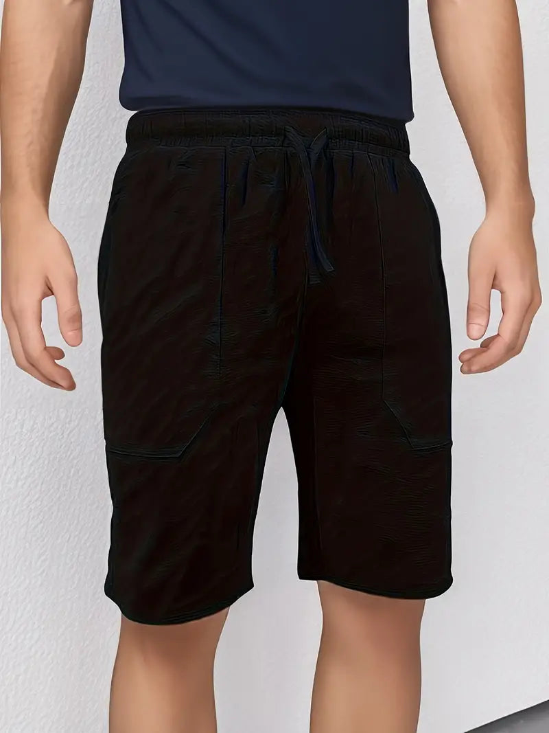 Homme portant un short noir décontracté avec cordon de serrage, poches latérales, sur fond blanc. Mode masculine, vêtements d'été confortables.