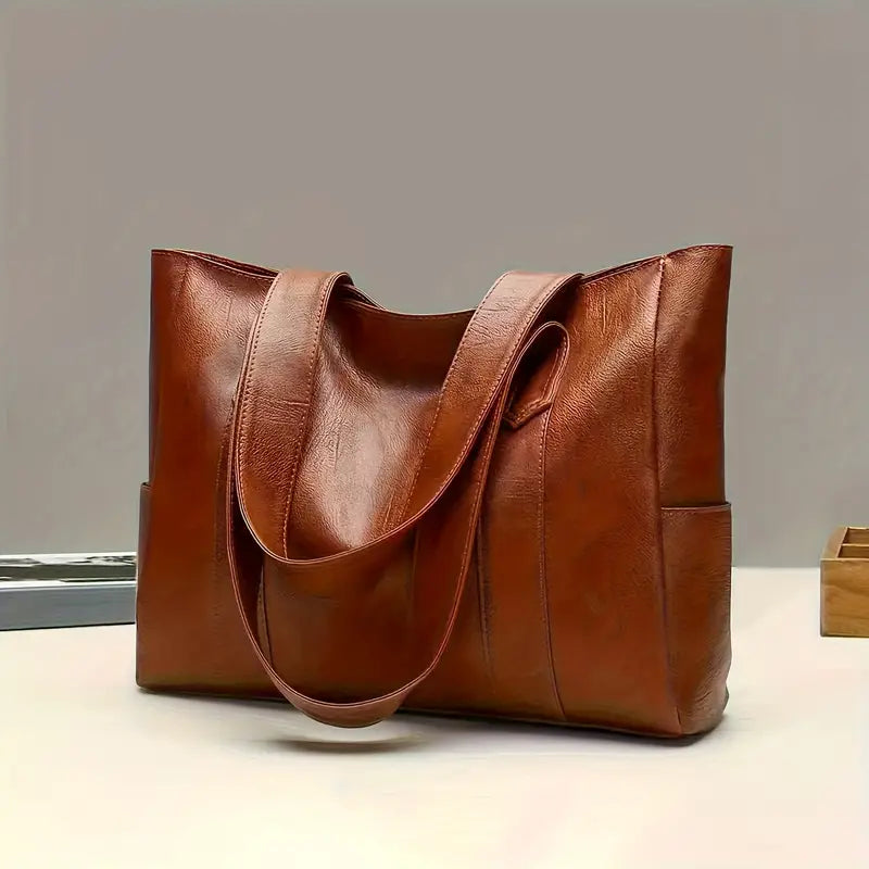 Sac à main en cuir marron élégant sur une table, design moderne et spacieux, idéal pour femme, accessoire mode tendance, qualité supérieure.
