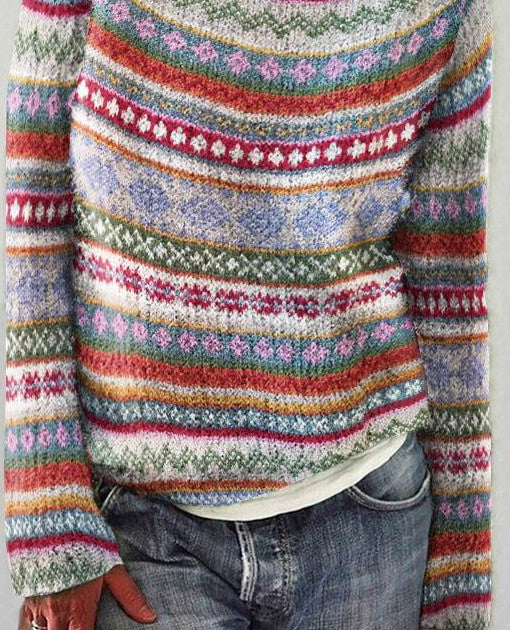 Pull en laine multicolore à motifs géométriques, rayures et fleurs, porté avec un jean décontracté. Mode automne-hiver, style bohème chic.