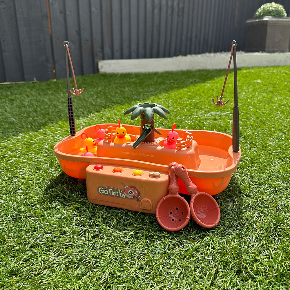 Jeu de pêche pour enfants sur gazon, avec cannes à pêche, poissons en plastique et palmier. Jouet éducatif extérieur, activité ludique.