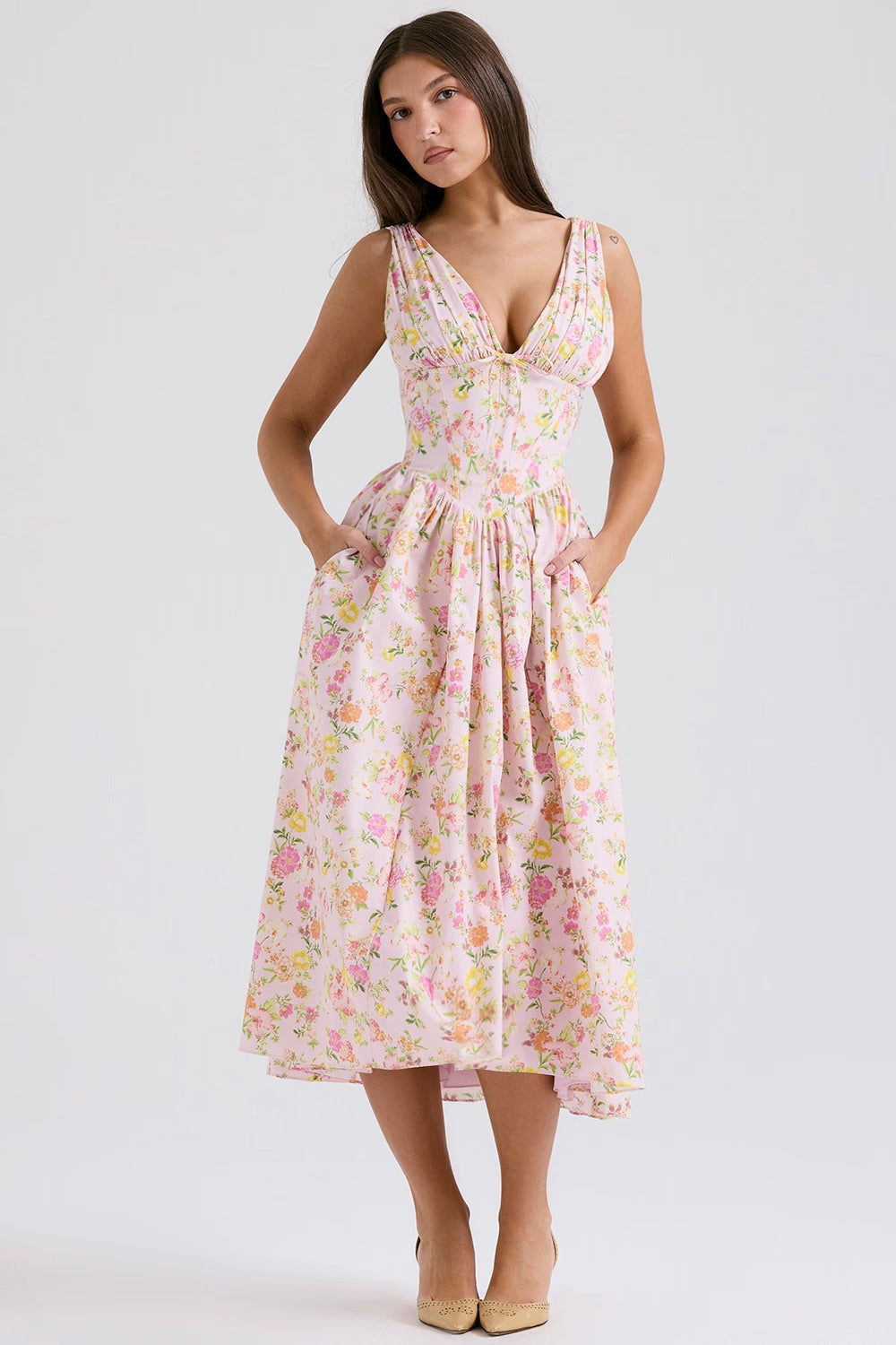 Robe longue fleurie rose avec décolleté en V, poches latérales, portée par une femme. Mode féminine élégante, tendance printemps-été.