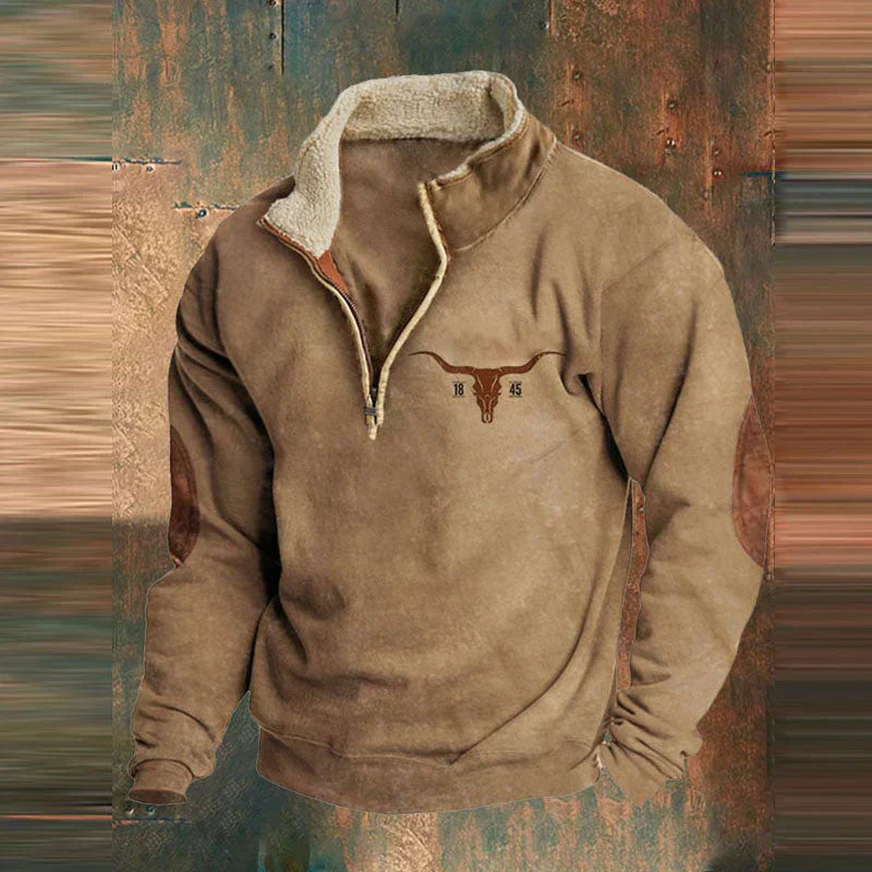 Sweat-shirt en laine marron avec col zippé, doublure en fourrure, coudières en cuir, et logo tête de taureau. Style western, mode automne-hiver.