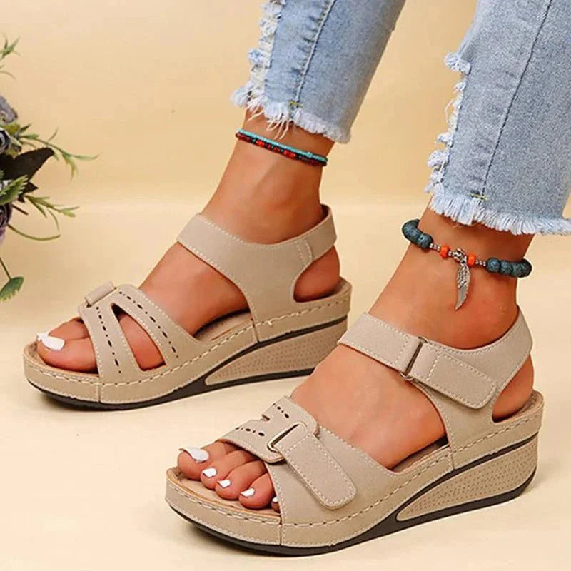 Sandales compensées beiges pour femme, avec lanières ajustables, portées avec un jean déchiré. Chaussures d'été tendance et confortables.