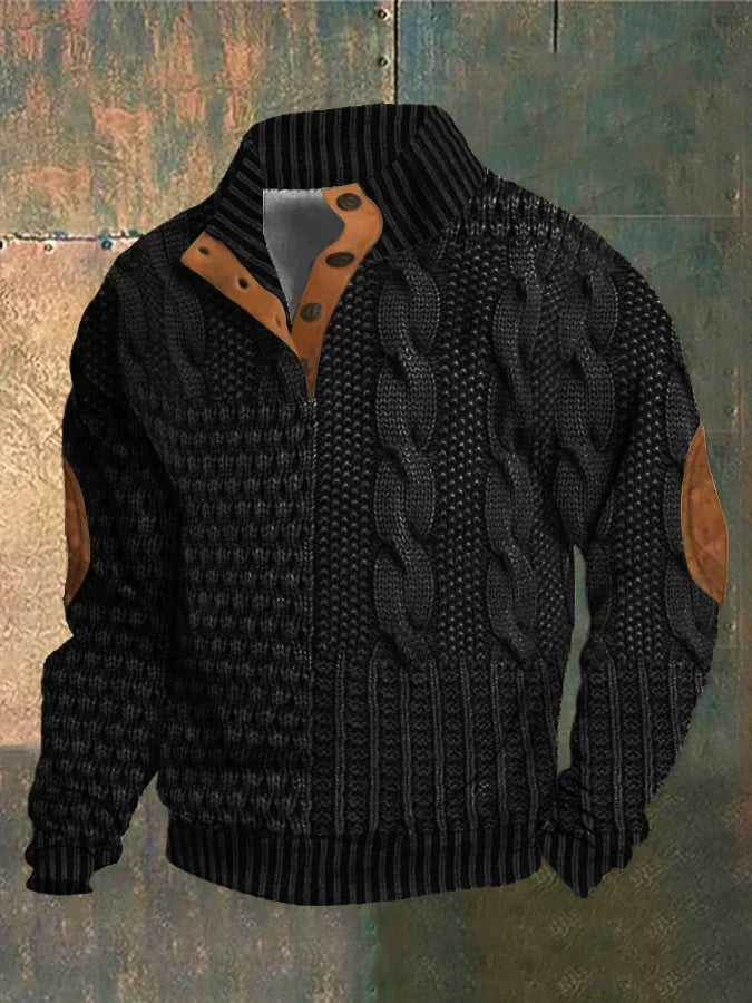 Veste en tricot noir avec motifs torsadés, col boutonné et coudières marron, posée sur fond texturé. Mode automne-hiver, style élégant.