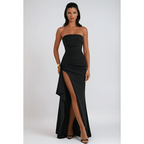 Femme en robe de soirée noire élégante avec fente haute, posant debout. Mode féminine, style glamour, tenue de soirée chic.