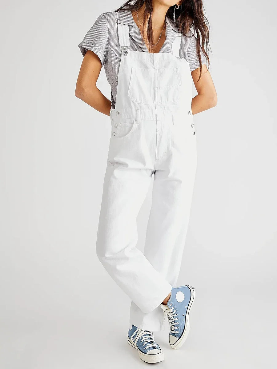 Femme portant une salopette blanche et un t-shirt rayé, baskets bleues Converse. Mode décontractée, style urbain, tendance féminine.