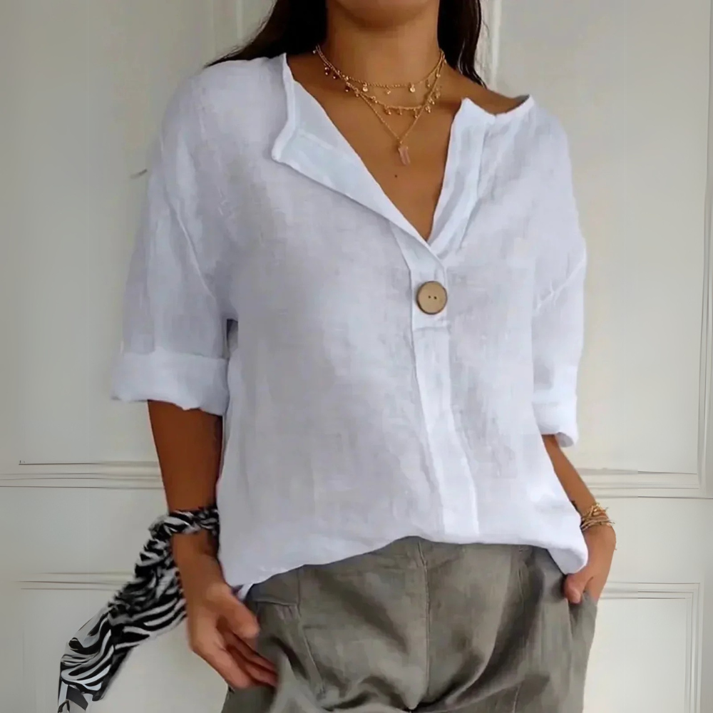 Chemise en lin blanc pour femme avec bouton en bois, manches retroussées, associée à un pantalon kaki. Style décontracté et élégant.