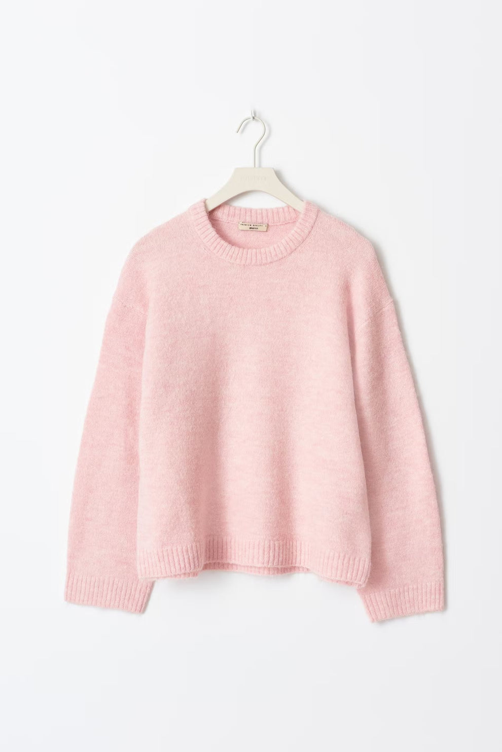 Pull rose en laine douce sur cintre blanc, manches longues, col rond, style décontracté. Mode féminine, vêtement d'hiver, tendance cosy.