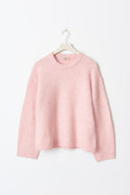 Pull rose en laine douce sur cintre blanc, manches longues, col rond, style décontracté. Mode féminine, vêtement d'hiver, tendance cosy.