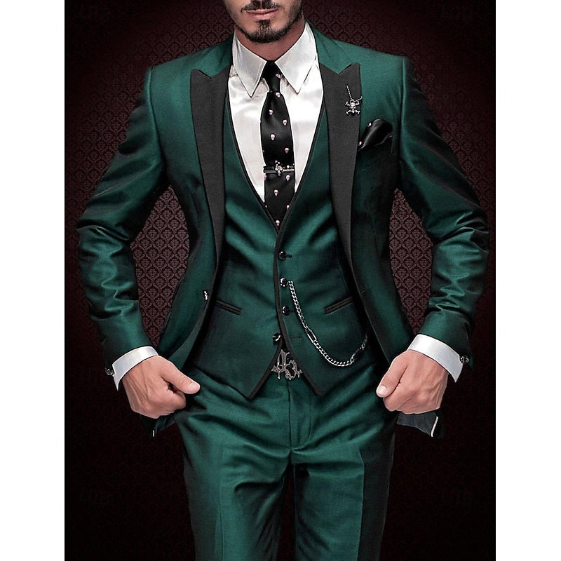 Homme en costume vert élégant avec cravate noire à motifs, gilet assorti et chaîne de montre, sur fond texturé sombre. Mode masculine chic.