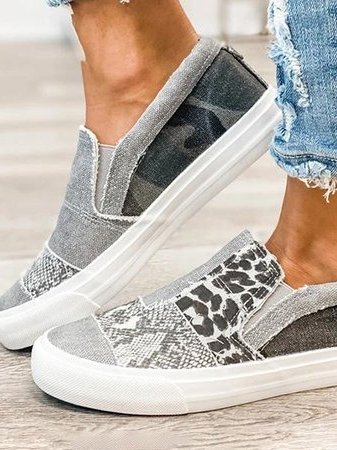 Chaussures slip-on grises à motifs léopard et camouflage, portées avec un jean déchiré. Style décontracté, tendance et moderne.