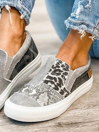 Chaussures slip-on grises avec motifs léopard et serpent, portées avec un jean déchiré. Style décontracté, tendance et moderne.