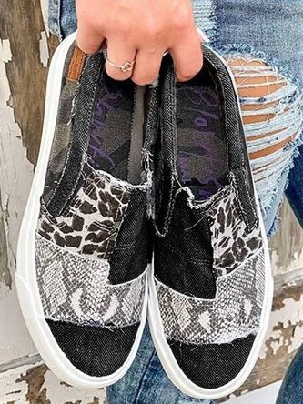 Chaussures slip-on en denim noir avec motifs léopard et serpent, semelle blanche. Mode décontractée, tendance urbaine, style unique.