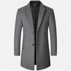 Manteau gris élégant pour homme, coupe longue, col à revers, doublure noire matelassée, idéal pour l'hiver et les occasions formelles.