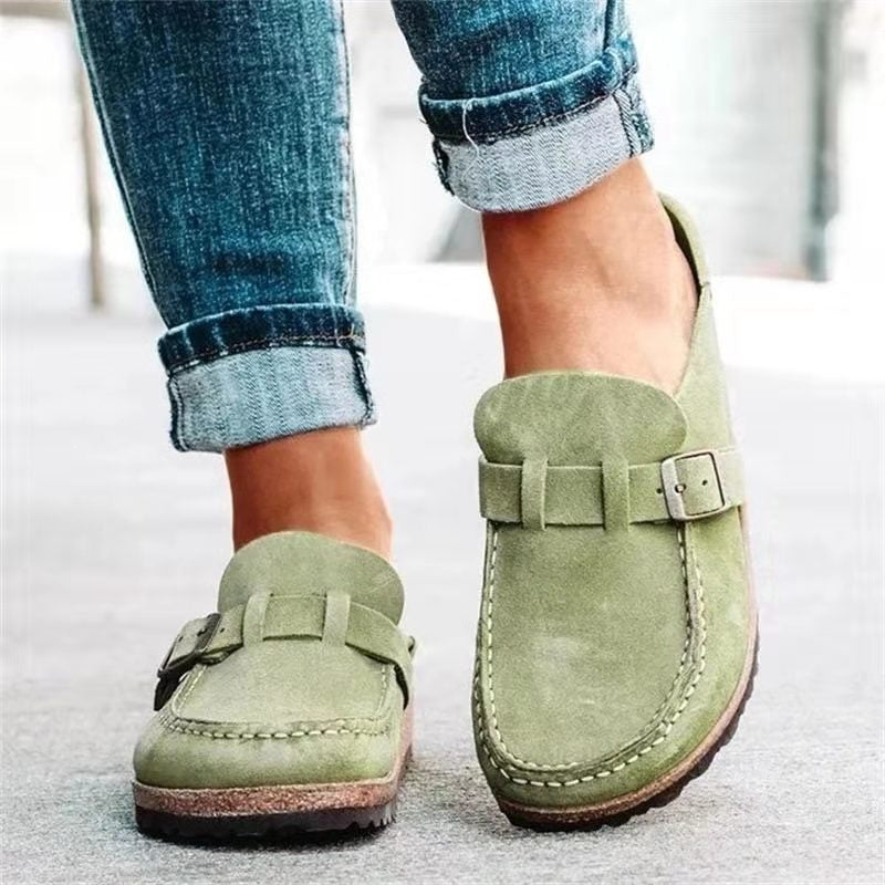 Mocassins verts en daim pour femme, avec boucle décorative, portés avec un jean retroussé. Chaussures confortables et élégantes pour un look décontracté.