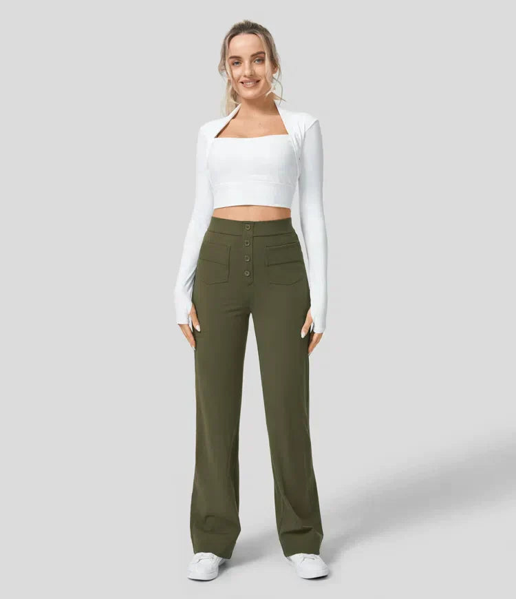 Femme portant un haut blanc à manches longues et un pantalon vert olive taille haute avec boutons, posant sur fond gris. Mode féminine élégante.