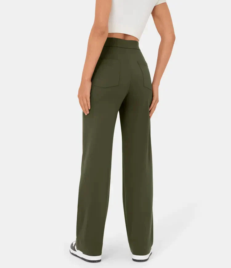 Femme portant un pantalon vert olive ample, taille haute, avec poches arrière, associé à un t-shirt blanc et des baskets noires.