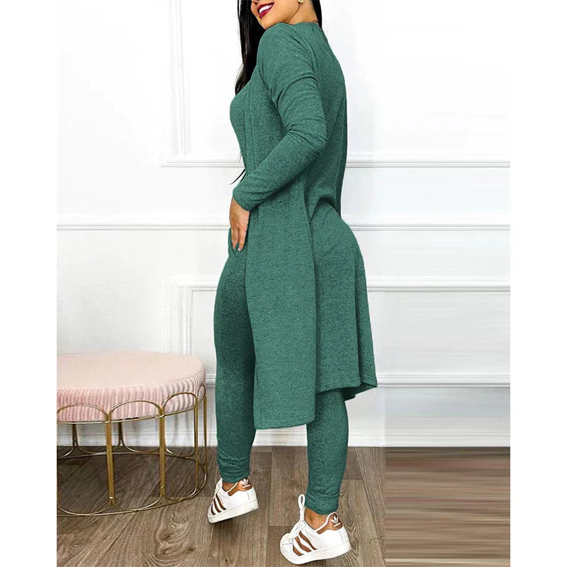 Femme portant un ensemble vert en tricot, tunique longue et leggings, posant dans un intérieur moderne. Mode féminine, tenue décontractée élégante.