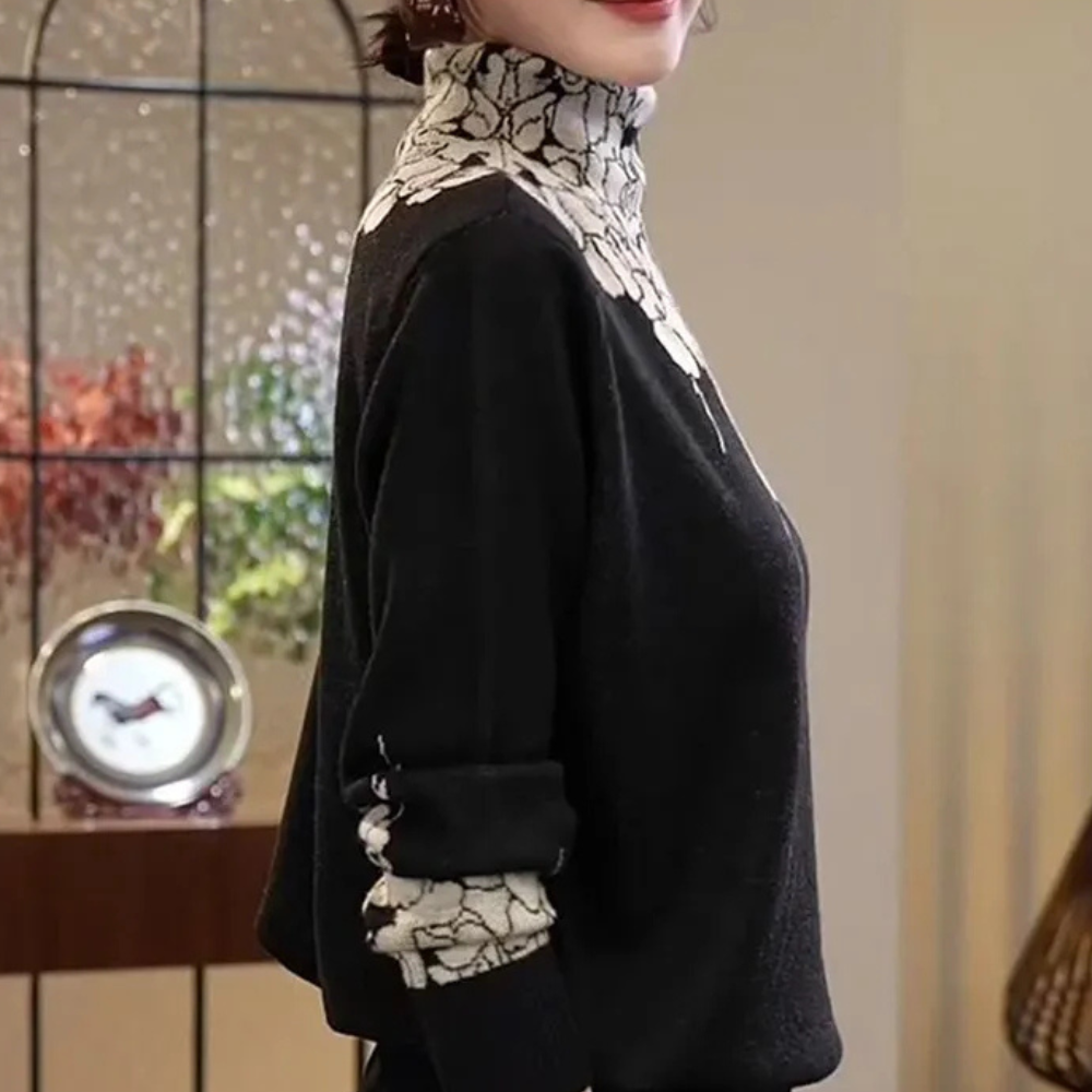Femme portant un pull noir à col roulé avec motifs blancs, debout près d'une horloge vintage. Mode élégante, style automne-hiver.