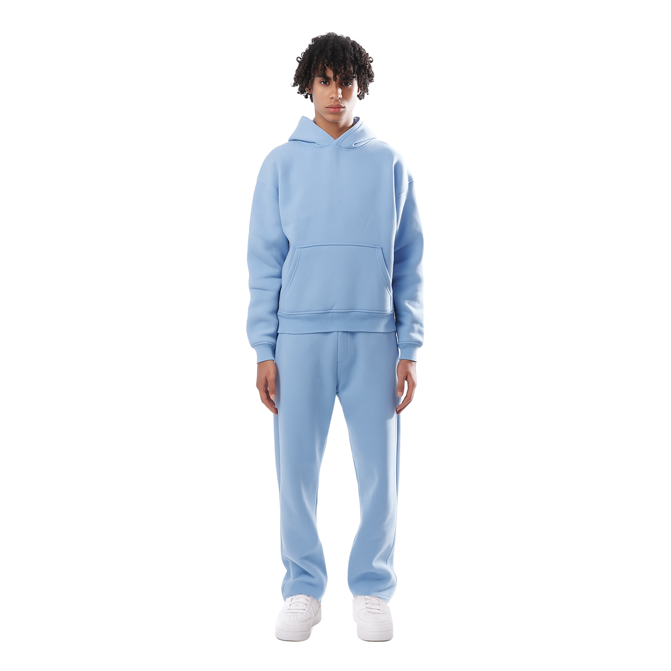 Jeune homme portant un survêtement bleu clair avec capuche, debout sur fond blanc. Mode décontractée, style urbain, vêtements confortables.