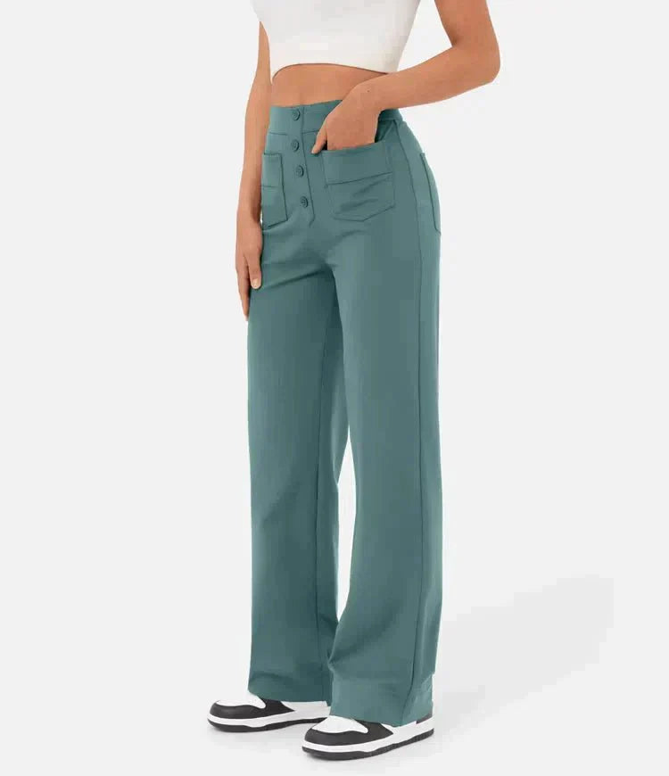 Femme portant un pantalon large vert avec poches, taille haute, associé à un haut blanc court et des baskets noires et blanches. Mode décontractée.