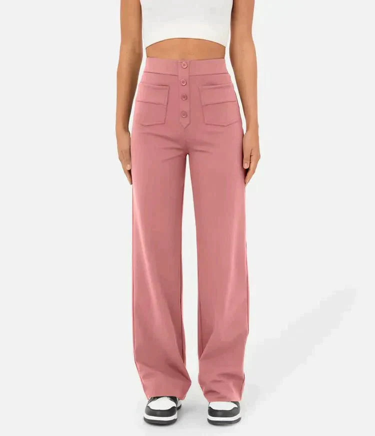 Femme portant un pantalon large rose taille haute avec boutons, poches avant, et un haut blanc court. Mode féminine, style décontracté, tendance.
