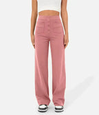 Femme portant un pantalon large rose taille haute avec boutons, poches avant, et un haut blanc court. Mode féminine, style décontracté, tendance.