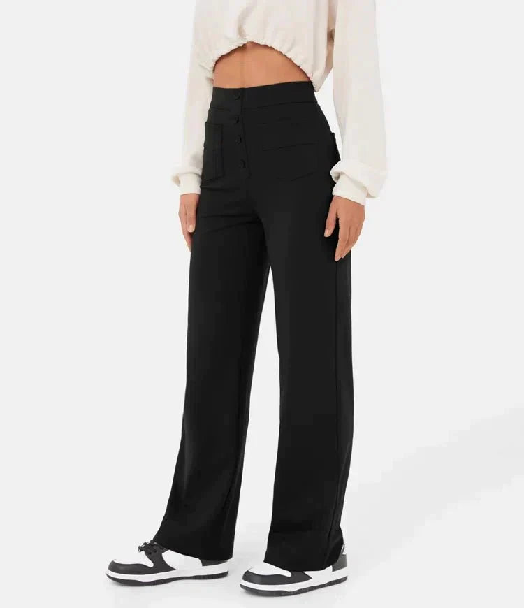 Pantalon noir taille haute pour femme, coupe large, porté avec un haut blanc court et des baskets noires et blanches. Mode féminine élégante.