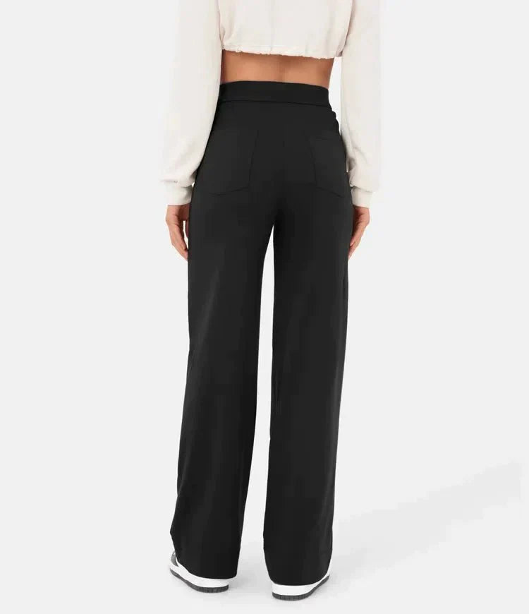 Femme portant un pantalon noir large, taille haute, avec un haut blanc court. Mode féminine élégante, vue de dos, style décontracté.