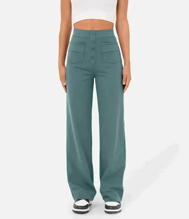 Femme portant un pantalon large bleu-vert taille haute avec boutons, poches avant, et un haut blanc court. Mode féminine élégante et moderne.