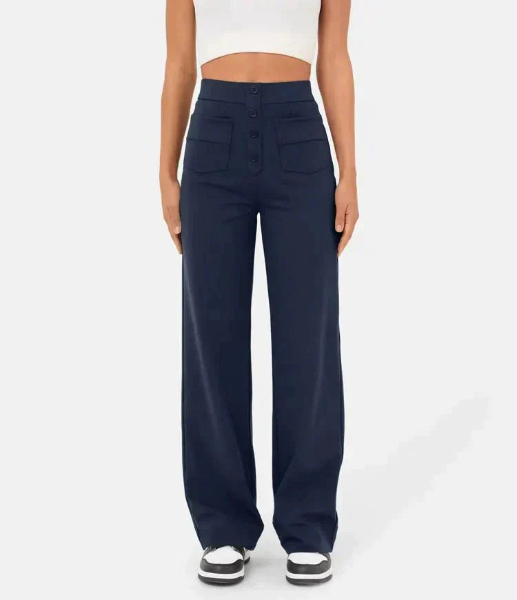 Pantalon large bleu marine taille haute pour femme, avec boutons et poches avant, porté avec un haut blanc. Mode féminine élégante et moderne.