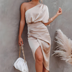 Robe élégante en satin beige asymétrique, femme posant avec sac à main blanc à chaîne dorée, décor pampas, mode chic et tendance.