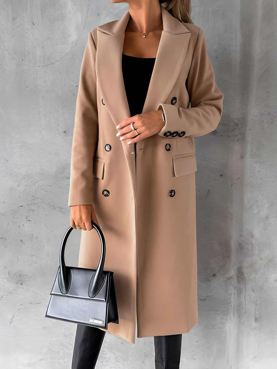 Femme portant un manteau beige élégant, tenant un sac à main noir moderne. Mode automne, style chic, tenue sophistiquée, accessoires tendance.