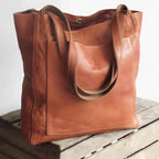 Sac cabas en cuir marron sur une caisse en bois, élégant et spacieux, idéal pour le shopping ou le bureau. Accessoire mode tendance et pratique.