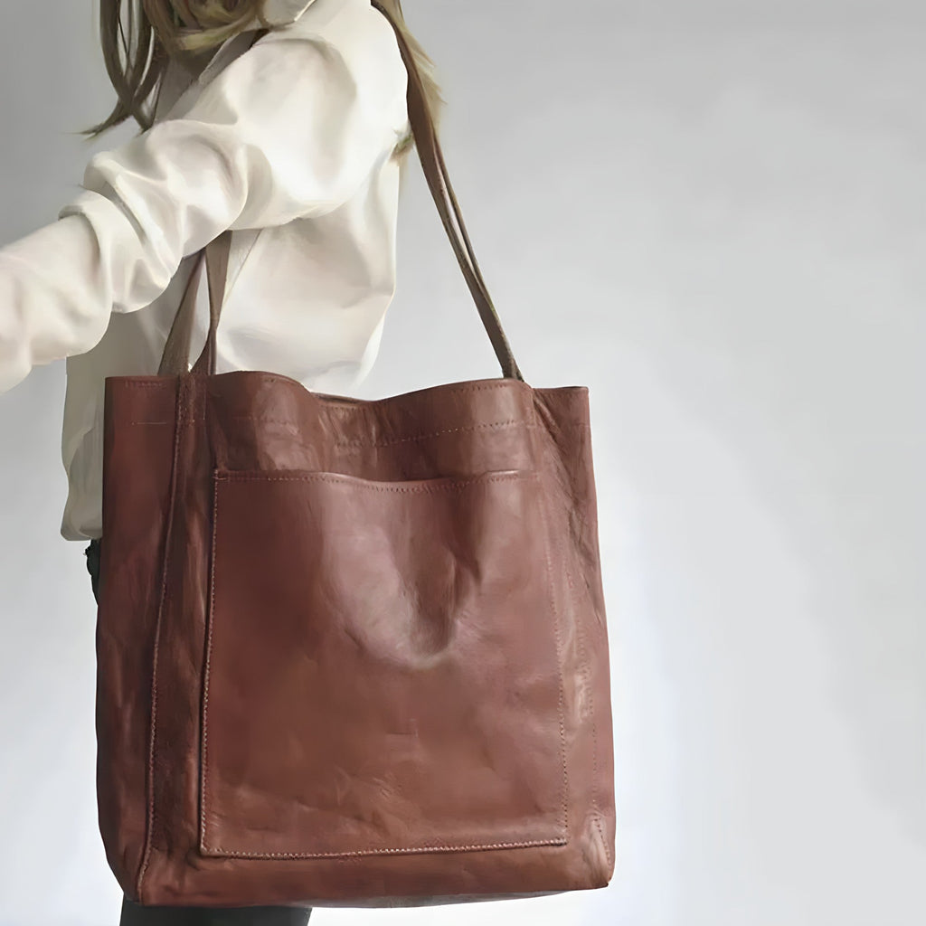 Sac en cuir marron porté par une femme en chemise blanche, design élégant et minimaliste, idéal pour mode urbaine et accessoires tendance.