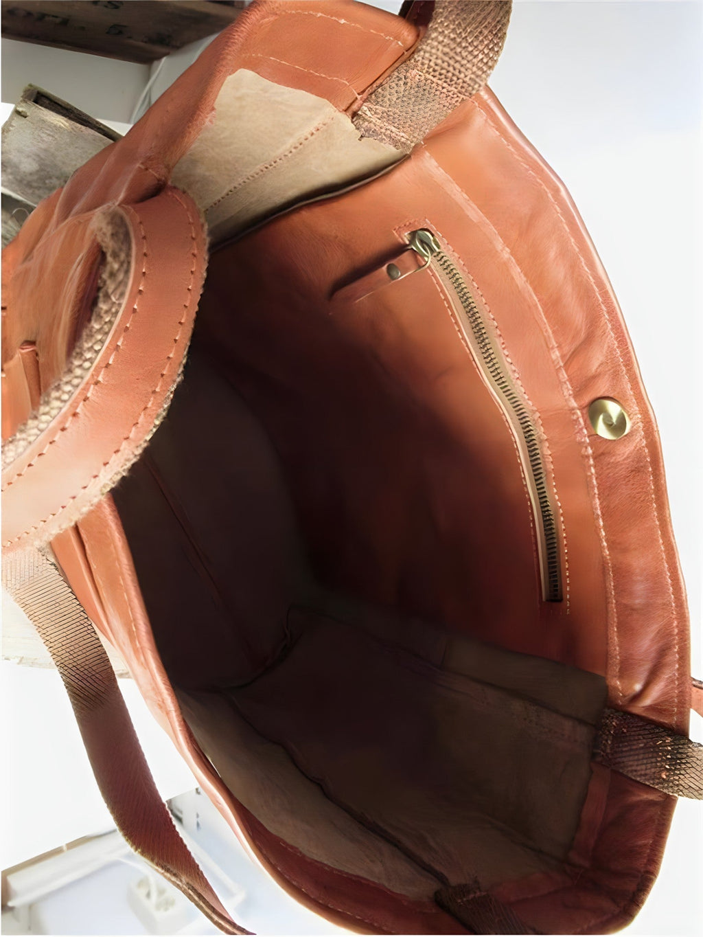 Sac à main en cuir marron ouvert, montrant une poche intérieure zippée et une fermeture à bouton-pression. Accessoire mode femme élégant et pratique.