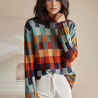 Femme portant un pull à carreaux colorés, manches longues, avec un motif géométrique, sur fond neutre. Mode automne-hiver, style décontracté.