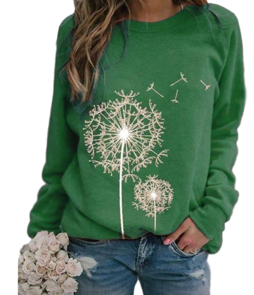 Femme portant un pull vert avec motif pissenlit, tenant un bouquet de roses blanches. Mode décontractée, tendance automne, style floral.