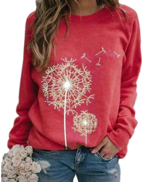 Femme portant un pull rouge avec motif pissenlit blanc, tenant un bouquet de roses blanches. Mode décontractée, tendance automne-hiver.