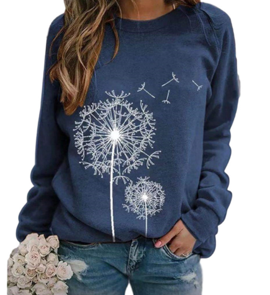 Femme portant un pull bleu avec motif de pissenlit blanc, tenant un bouquet de roses blanches. Mode décontractée, tendance automne-hiver.