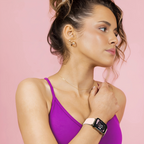 Femme portant une montre connectée sur fond rose, habillée d'un débardeur violet. Accessoire technologique moderne, mode féminine, style sportif.