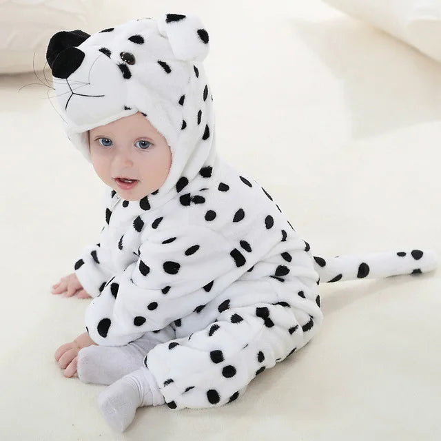 Bébé en costume de dalmatien, assis sur un tapis blanc. Pyjama à pois noirs, capuche avec oreilles et queue. Tenue mignonne pour enfant.