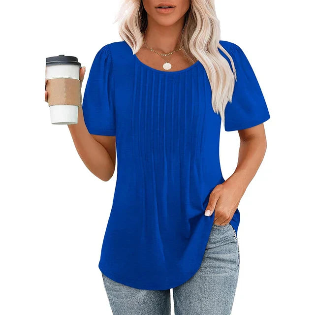 Femme portant un t-shirt bleu à manches courtes, tenant un gobelet de café. Mode décontractée, style estival, cheveux blonds, jeans.