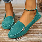 Chaussures mocassins vert turquoise en daim pour femme, ornées de perles, posées sur un sol en bois. Mode féminine, style décontracté, tendance.