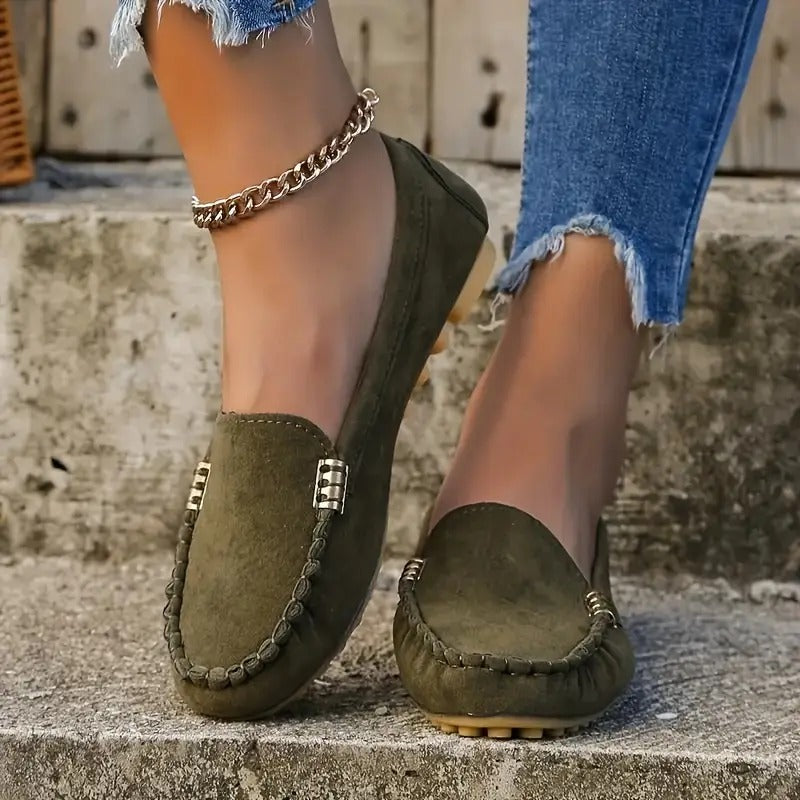 Chaussures mocassins vert olive pour femme, ornées de chaînes dorées, portées avec un jean déchiré. Mode féminine, style décontracté, tendance chaussures.