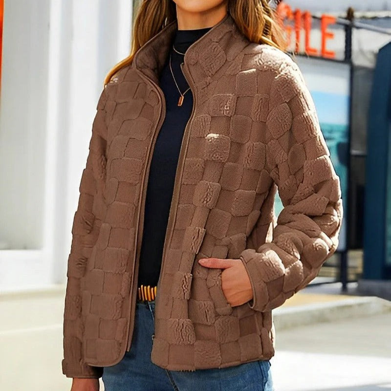 Femme portant une veste matelassée marron, style décontracté, devant un bâtiment urbain. Mode automne, tendance vestimentaire féminine.