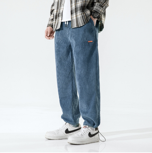 Pantalon en velours côtelé bleu pour homme, style décontracté, avec chemise à carreaux et baskets blanches Nike. Mode masculine tendance.