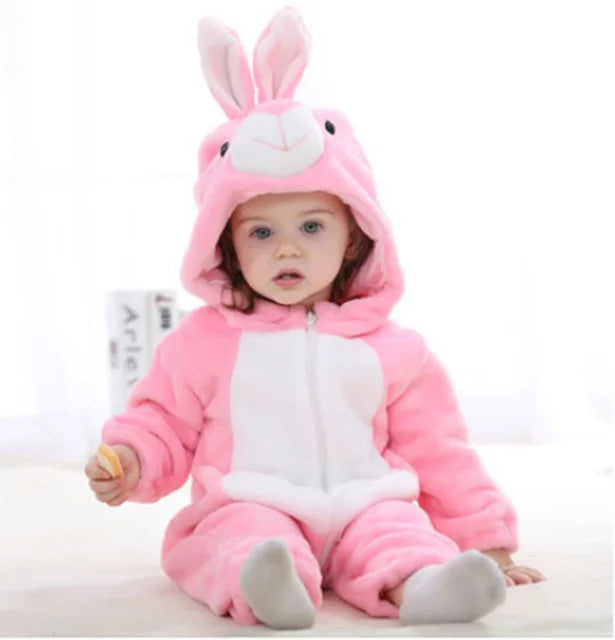 Enfant en combinaison rose de lapin, assis sur un sol clair. Pyjama bébé mignon, capuche avec oreilles de lapin, tenue chaude et douce.