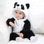 Bébé en combinaison panda noir et blanc, assis sur un canapé blanc. Costume mignon, capuche avec oreilles et visage de panda. Vêtements pour enfants.